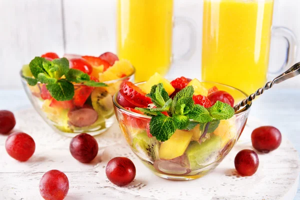 Fruitsalade met munt en sinaasappelsap in glaswerk op een houten achtergrond kleur — Stockfoto