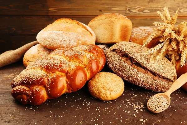 Různé chleba s ušima a slunečnicová semínka na dřevěné pozadí — Stock fotografie
