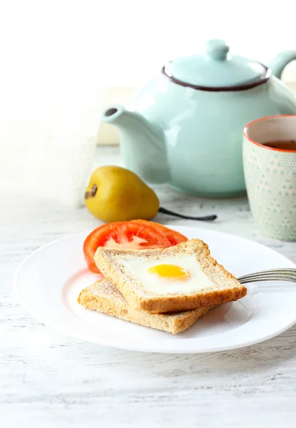Rührei mit Brot auf Teller mit Tasse Tee auf hellem Hintergrund — Stockfoto