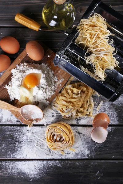 Kovové těstoviny maker stroj a ingredience pro těstoviny na dřevěné pozadí — Stock fotografie