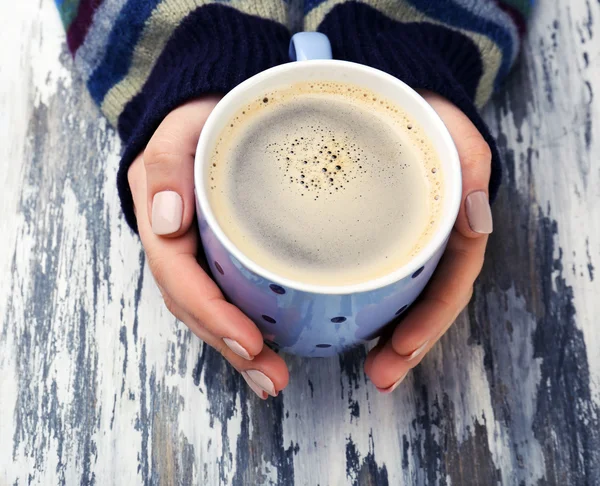 Mains féminines tenant une tasse de café sur fond en bois — Photo