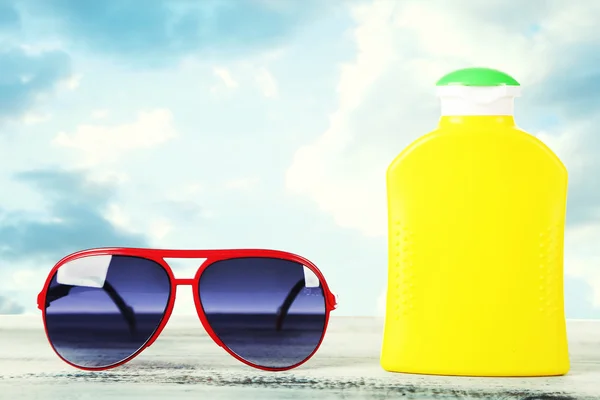 Bottle of suntan cream with sunglasses on table Bottle with suntan cream on table isolated on white — Stock Photo, Image