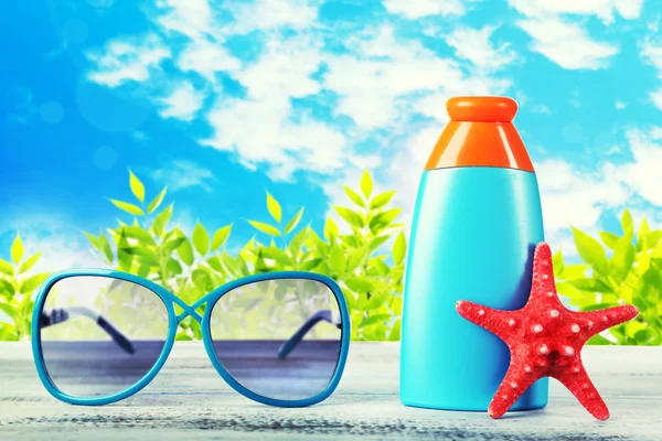 Bottle of suntan cream with sunglasses and sea star on table isolated on white — Stock Photo, Image