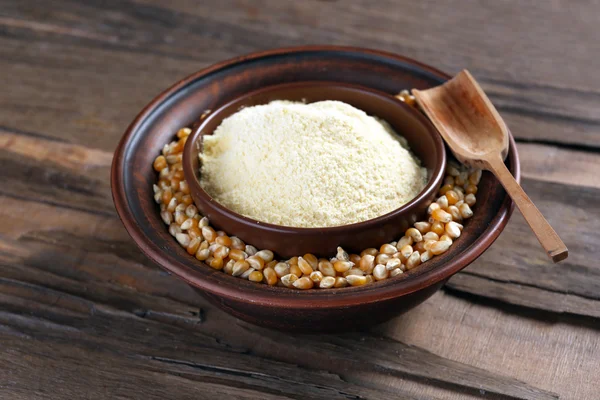 Flour and corn grains in bowls with spoon on wooden background — Stock Photo, Image