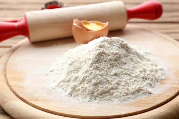 Heap of flour on cutting board with egg and plunger on wooden table — Stock Photo, Image