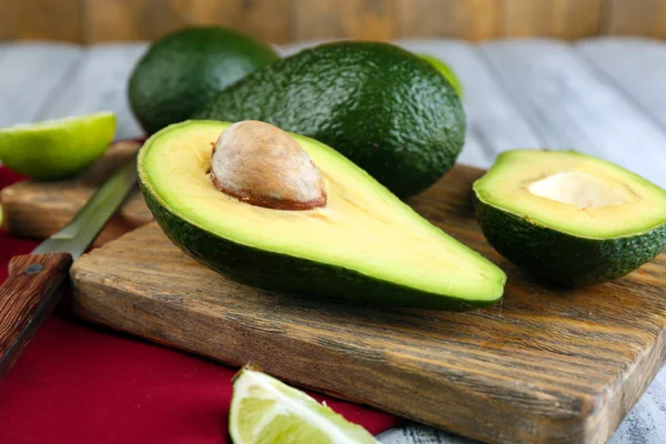 Aguacate con limas y cuchillo en tabla de cortar en primer plano —  Fotos de Stock