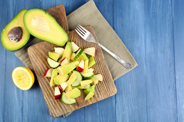 Aguacate en rodajas y manzana sobre tabla de cortar sobre fondo de madera —  Fotos de Stock