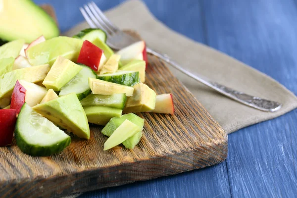 Sliced avocado and apple on cutting board on wooden background — Stock Photo, Image