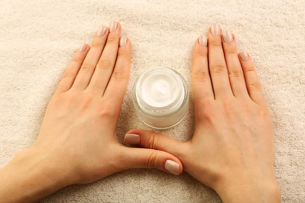 Vrouwelijke handen met potje crème op stof achtergrond — Stockfoto