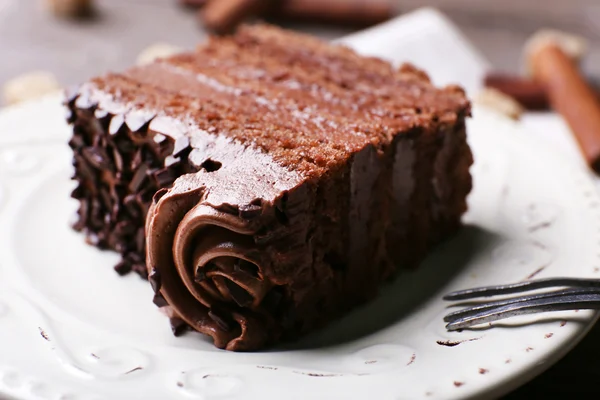 Tasty piece of chocolate with lump sugar and cinnamon sticks cake on wooden table background — Stock Photo, Image