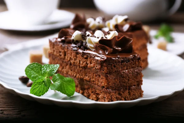 Peça saborosa de bolo de chocolate com hortelã em fundo de mesa de madeira — Fotografia de Stock