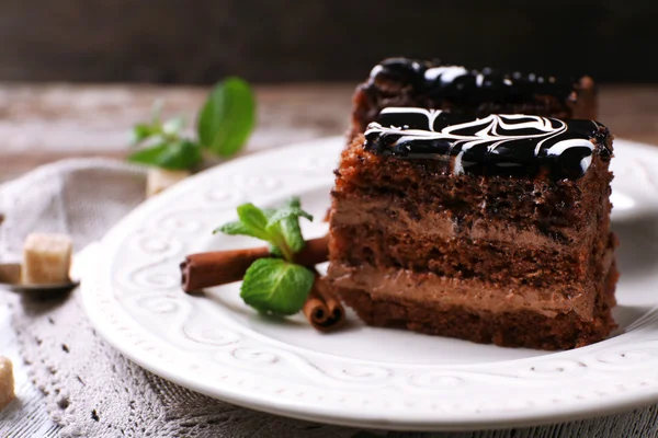 Вкусные кусочки шоколадного торта с мятой и корицей на деревянном столе и темном фоне — стоковое фото