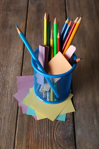 Colorful pencils in metal holder with sticky notes on wooden planks background — Stock Photo, Image
