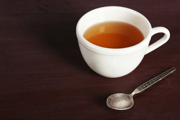 Cup of tea and spoon on color wooden table background — Stock Photo, Image