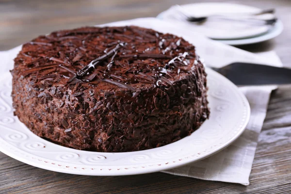 Köstliche Schokoladenkuchen auf Teller mit Serviette auf Holztischhintergrund — Stockfoto