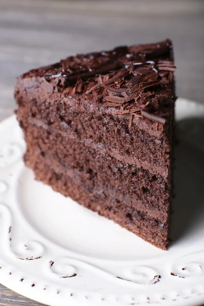 Delicious chocolate cake in white plate on wooden table background, closeup — Stock Photo, Image