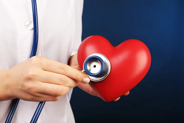 Mani medico con cuore e stetoscopio su sfondo blu — Foto Stock