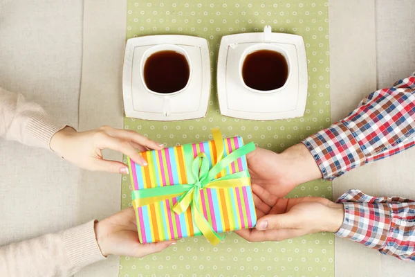 Mani femminili e maschili con tazze di tè e confezione regalo, primo piano — Foto Stock