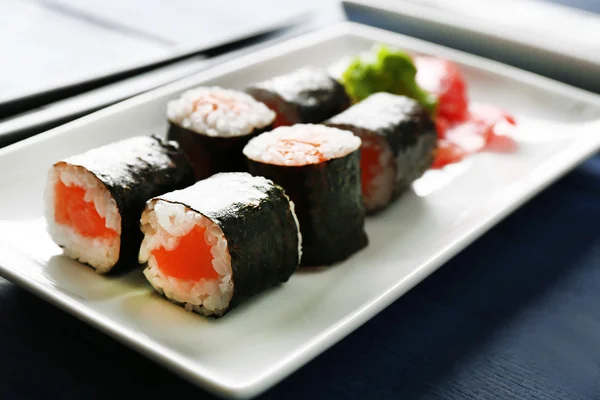 Rollos de sushi con salmón en plato, sobre fondo de madera —  Fotos de Stock