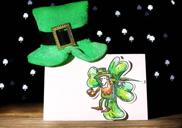 Tarjeta de felicitación para el día de San Patricio con sombrero de duende sobre mesa de madera sobre fondo de luces oscuras —  Fotos de Stock