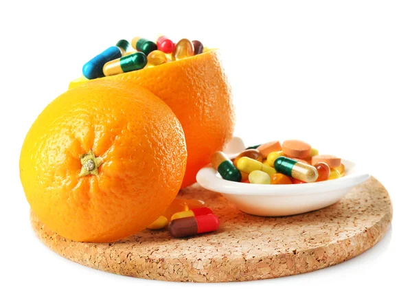 Frutta arancione e pillole colorate, isolate su bianco — Foto Stock