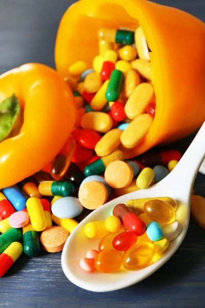 Orange pepper and colorful pills, on wooden background — Stock Photo, Image