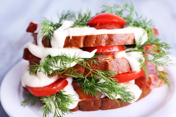 Сэндвич с сосисками, помидорами и майонезом на тарелке, крупным планом — стоковое фото