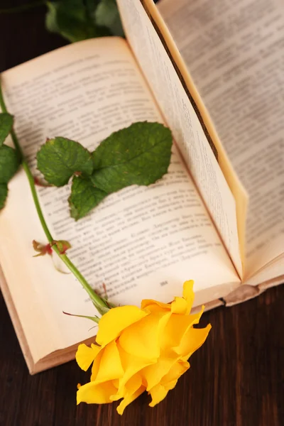 Libro con rosa amarilla sobre mesa de madera, primer plano — Foto de Stock