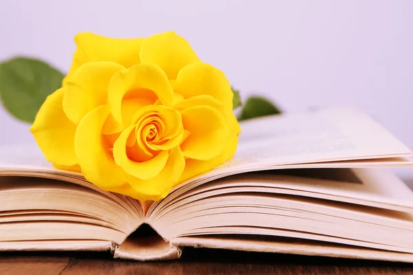 Livro com rosa amarela na mesa de madeira no fundo claro — Fotografia de Stock