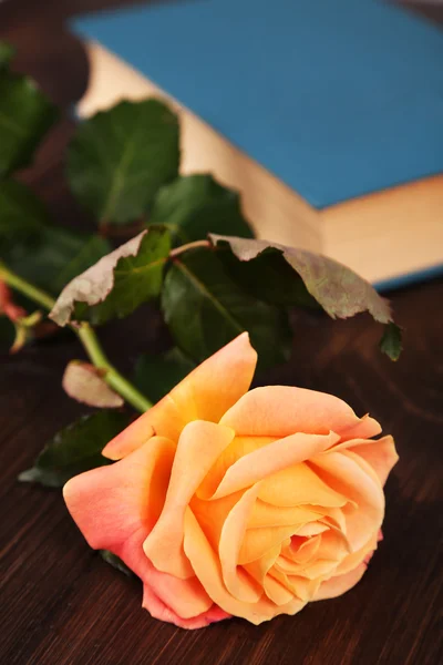 Beautiful rose with book on wooden table, closeup — Stock Photo, Image