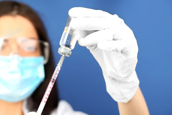 Ampola e seringa nas mãos do médico sobre fundo azul — Fotografia de Stock