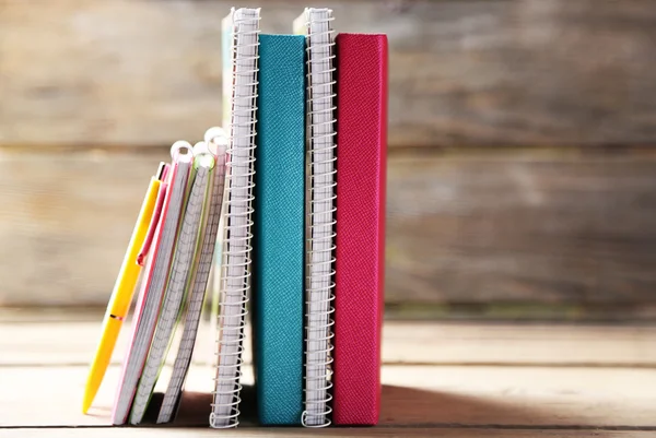Colorful notebooks and pen on old wooden table — Stock Photo, Image
