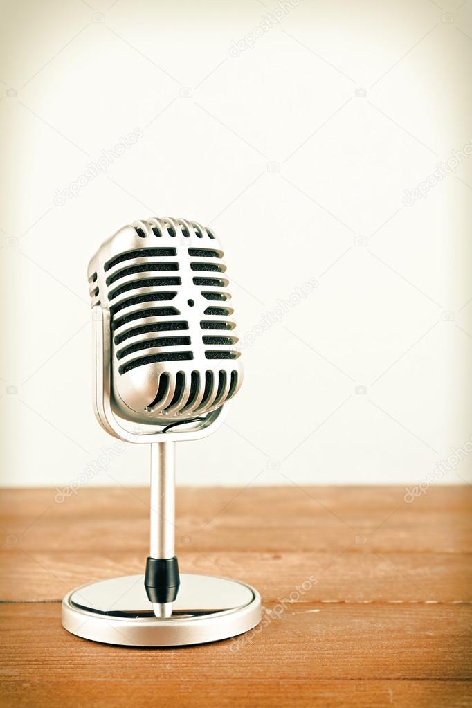 Retro microphone on wooden table on light background