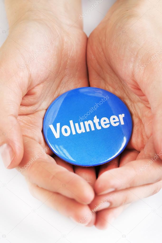 Round volunteer button in hands isolated on white