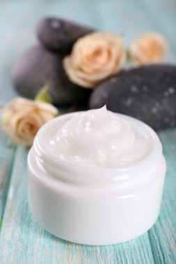 Çiçek ve spa taşlar ahşap arka plan üzerinde kozmetik krem