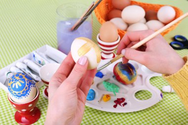 Renkli masa örtüsü arka plan üzerinde eller tarafından Paskalya yumurta boyama