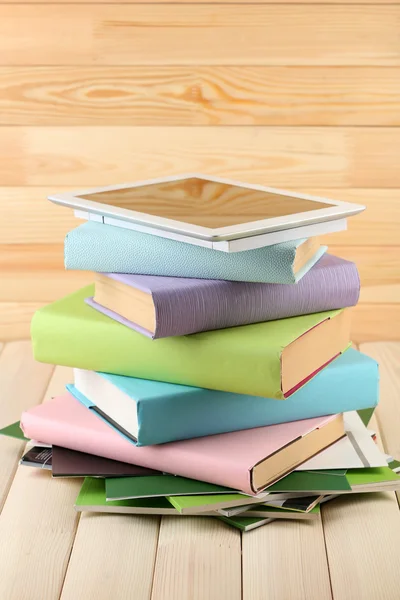 Tablette PC sur le dessus de pile de livres et de magazines sur fond en bois — Photo