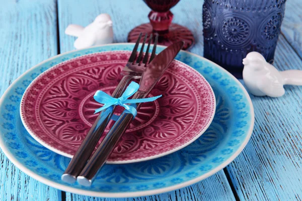 Empty colorful plate, glasses and silverware set on wooden table — Stock Photo, Image