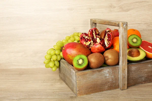 Assortment of exotic fruits in box on wooden background — Stock Photo, Image