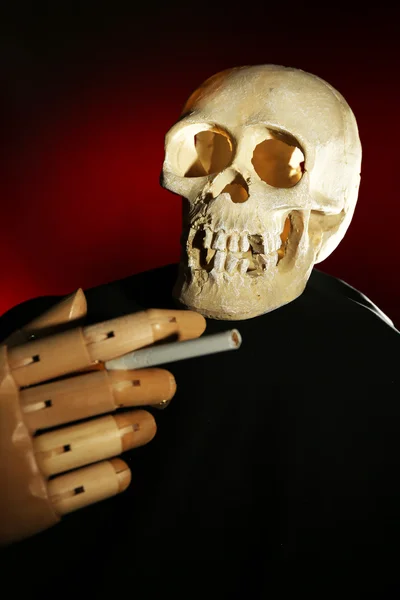 人类头骨和木制手与香烟在深色背景 — 图库照片