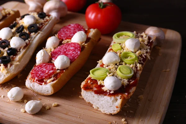 Diferentes sándwiches con verduras y queso en la tabla de cortar en primer plano — Foto de Stock