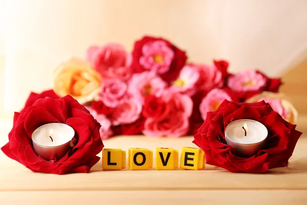 Декоративні літери, що формують слово "LOVE" з квітами та свічками на яскравому фоні — стокове фото