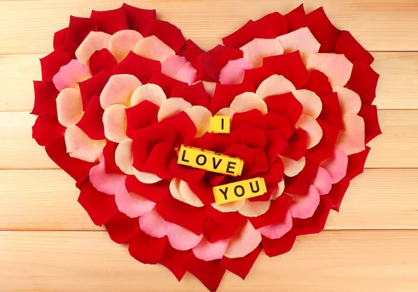 Words I Love You formado a partir de cubos sobre pétalos de rosas sobre fondo de madera — Foto de Stock