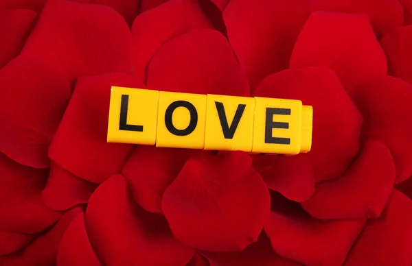 Decorative letters forming word LOVE on petals of roses background — Stock Photo, Image