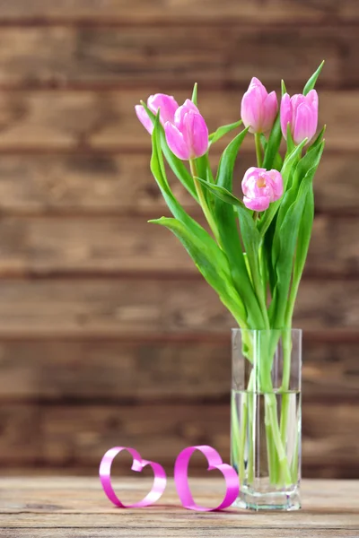 Hermosos tulipanes rosados en jarrón sobre mesa sobre fondo de madera — Foto de Stock