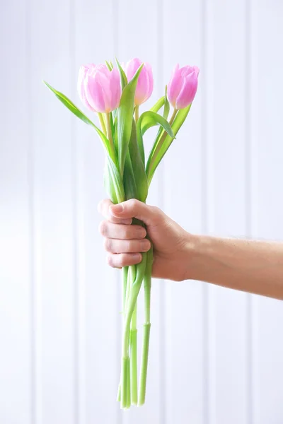 Hand holding beautiful pink tulips on wooden background — Stock Photo, Image