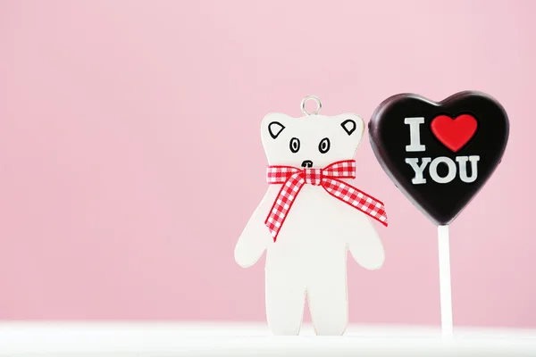 Coração doce com urso de brinquedo na mesa no fundo rosa — Fotografia de Stock