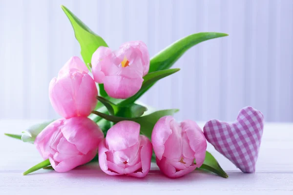 Linda tulipas rosa com coração decorativo em fundo de madeira — Fotografia de Stock