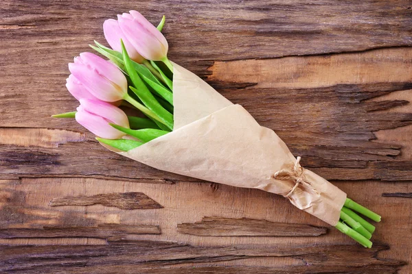 Hermosos tulipanes rosados en papel sobre fondo de madera — Foto de Stock