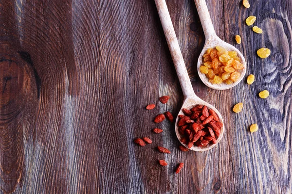 Raisins e Goji in cucchiai su sfondo rustico tavolo in legno — Foto Stock